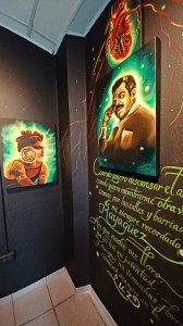 Firefly inspired portraits glowin green against a black background and green calligraphy on the wall.